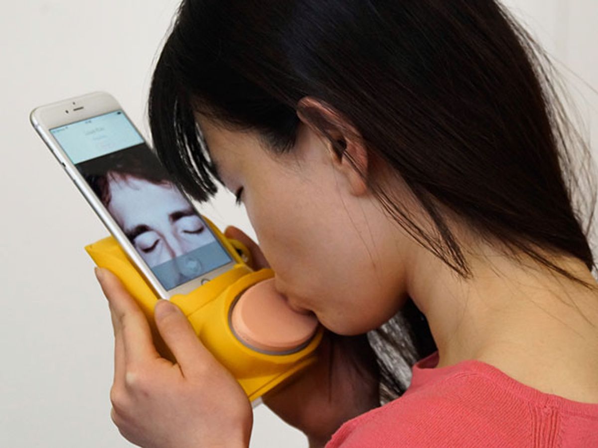 A woman kisses a plastic pad attached to her smartphone to send a virtual kiss to the person she's video chatting with.