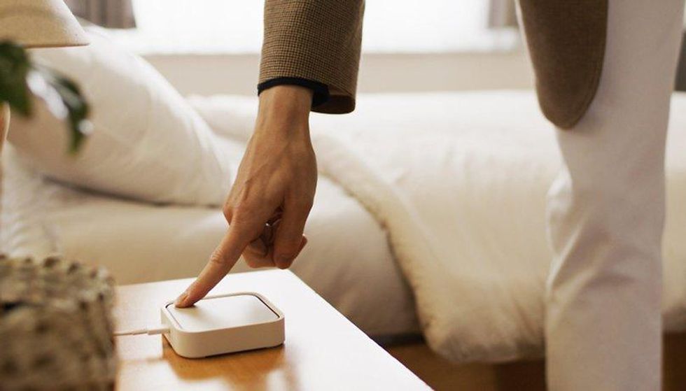 A woman pressing a button on a smart home device.
