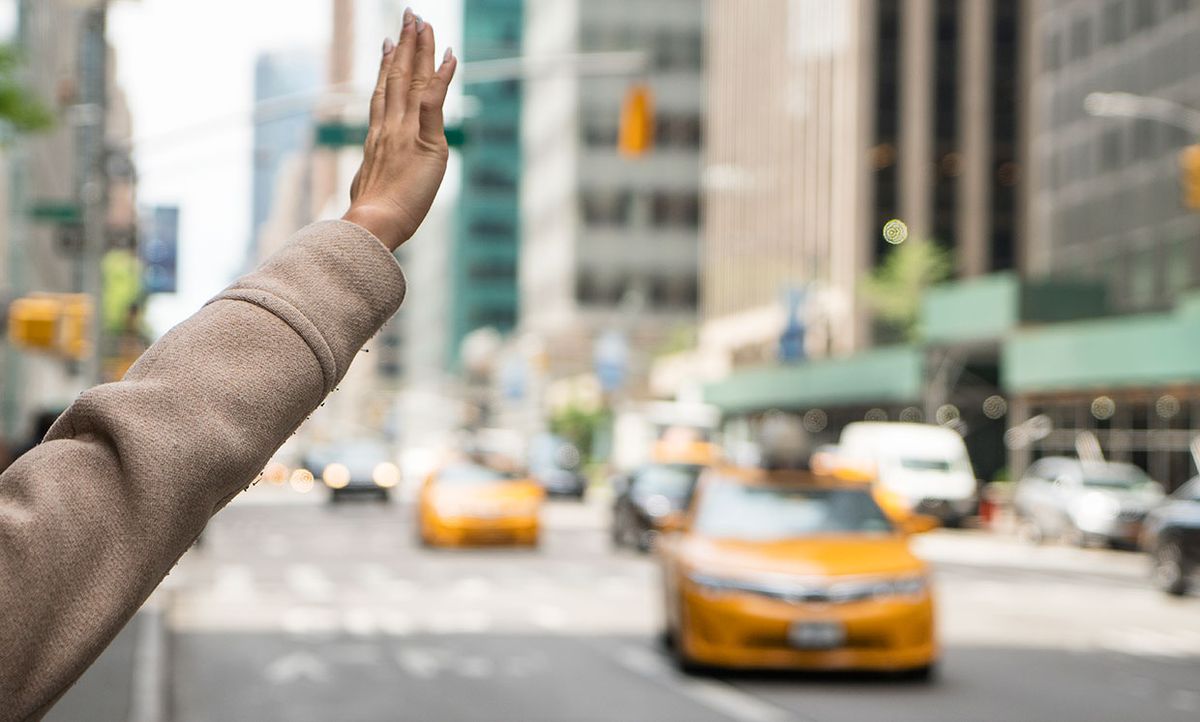 A woman's hand hails a taxi.