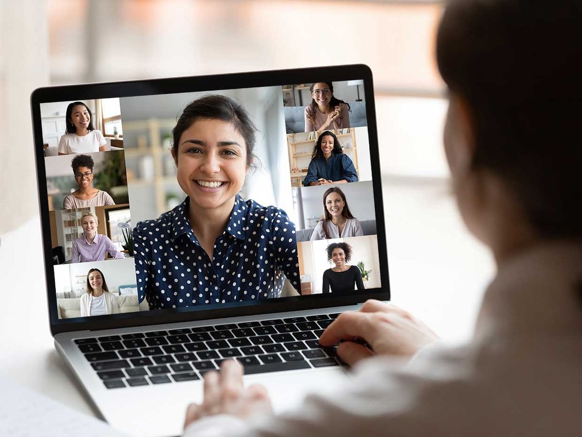 A woman who is talking on a group video call with a laptop.