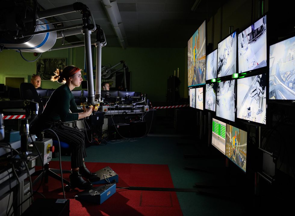 A women using robotic equipment in front of multiple screens.