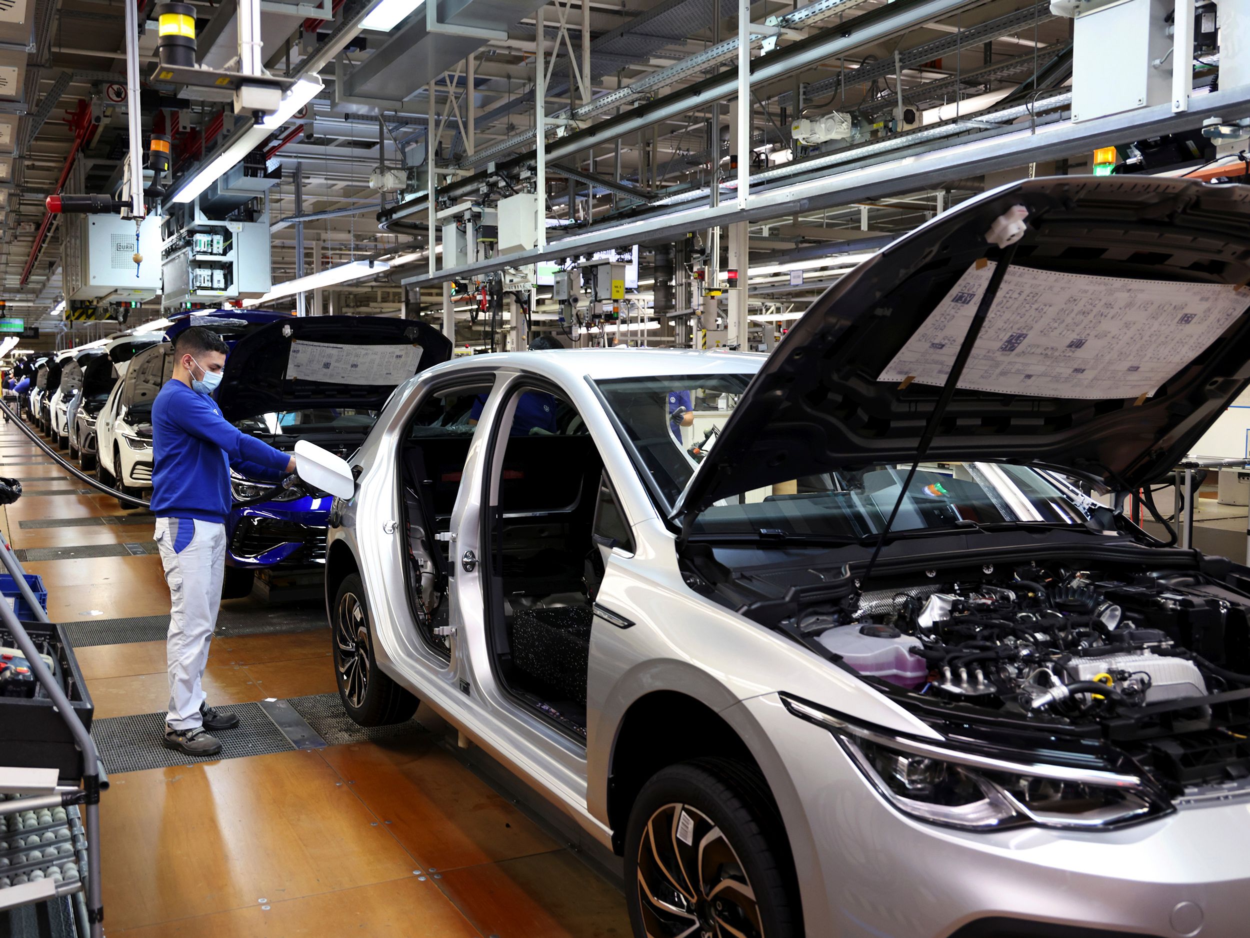 A worker fuels a Volkswagen Golf 8 automobile on the assembly line.