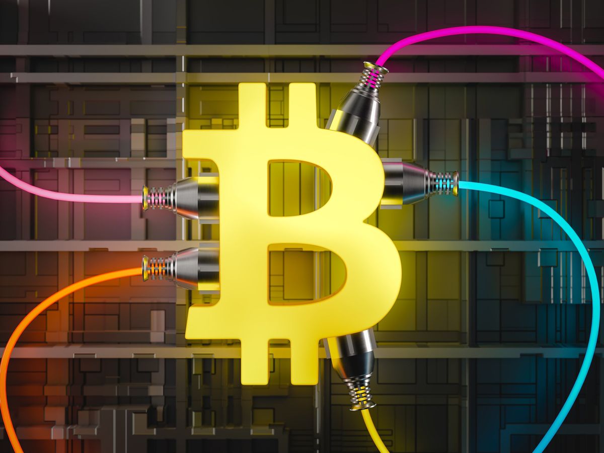 a yellow Bitcoin symbol with different colored power cords plugged in to it 