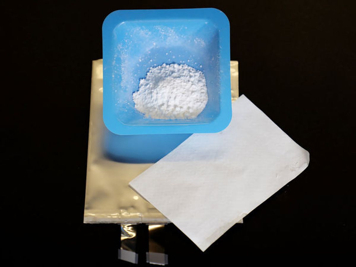 Adding powdered silica (in blue container) to the plastic layer (white sheet) that separates electrodes inside a test battery (gold bag) will prevent lithium-ion battery fires.