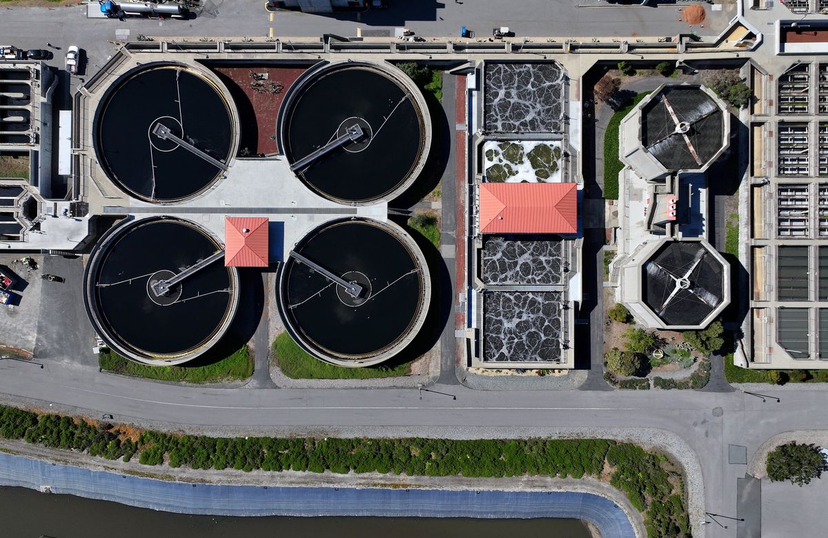 Aerial view of a wastewater treatment plant in California with large circular settling ponds.