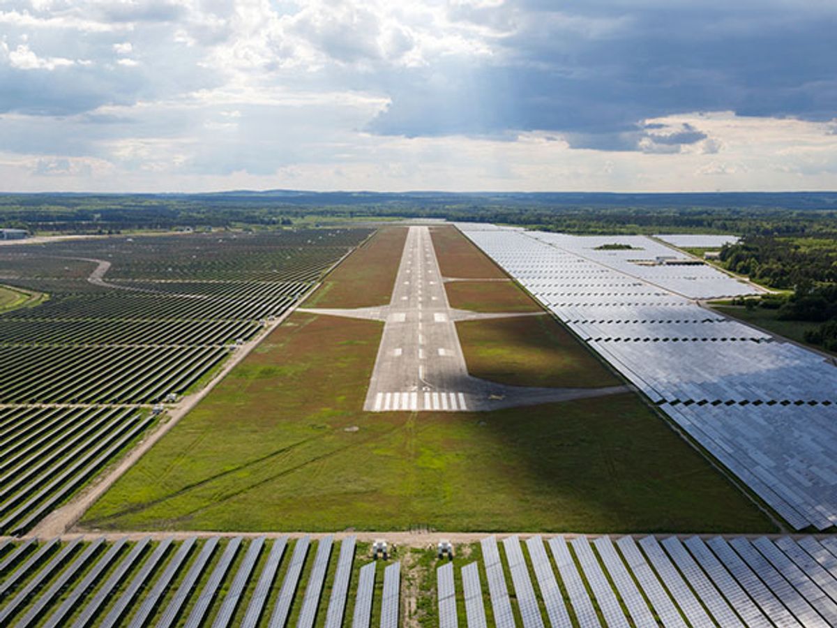Aerial view of an airport runway with solar PV arrays on all sides of the runway