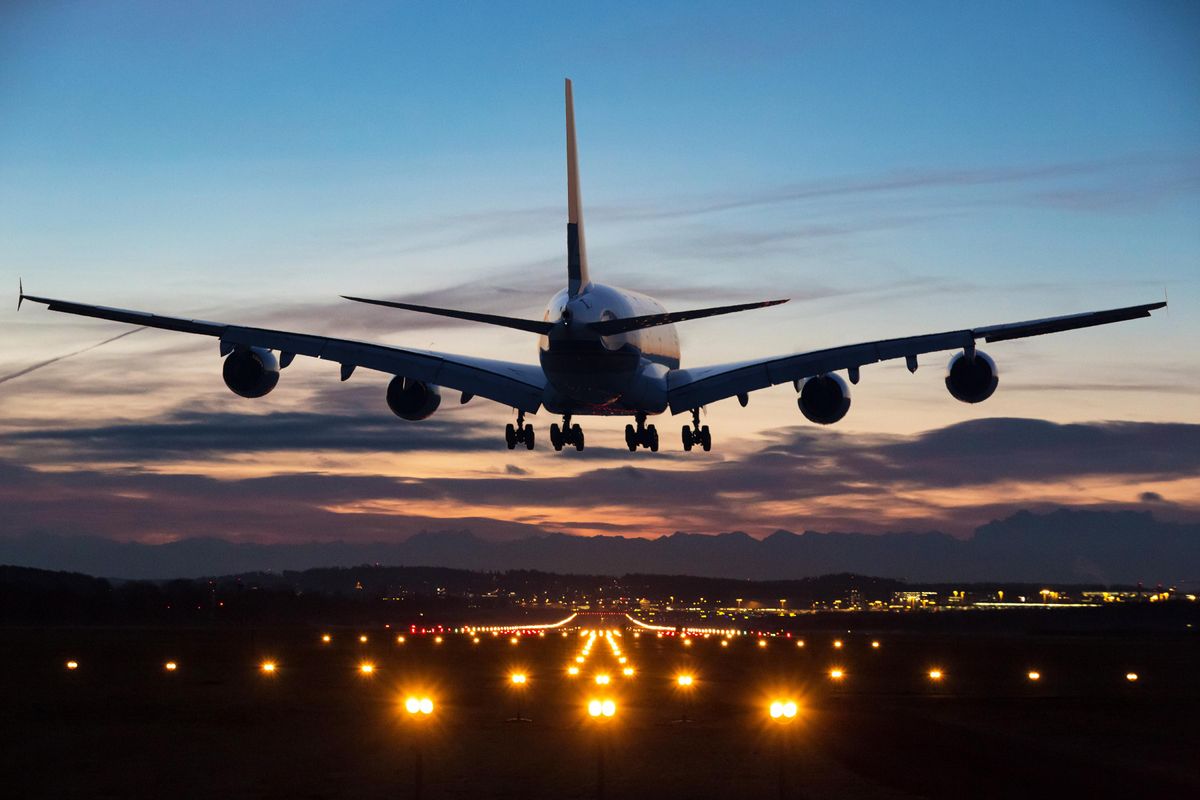 An airplane just before landing in the early morning. Runway lights can be seen in the foreground.