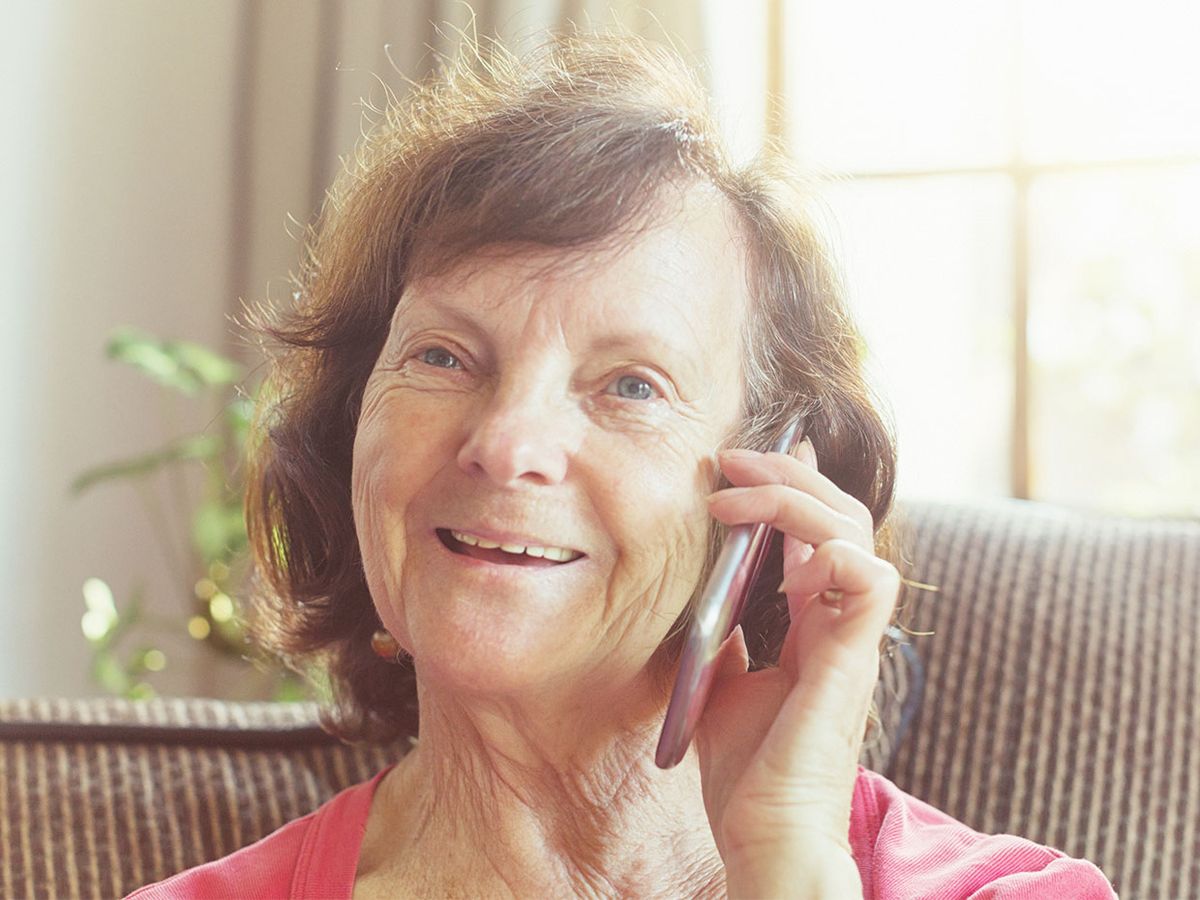 An elderly woman speaks on her phone