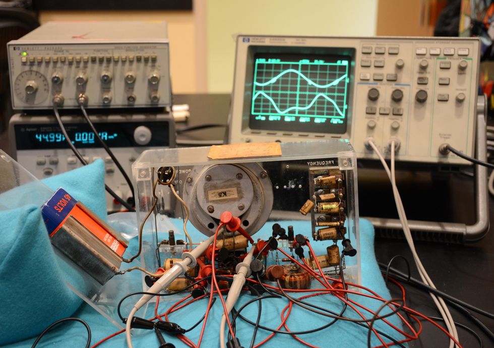 An electronic gadget is connected with wires to an oscilloscope and other equipment.