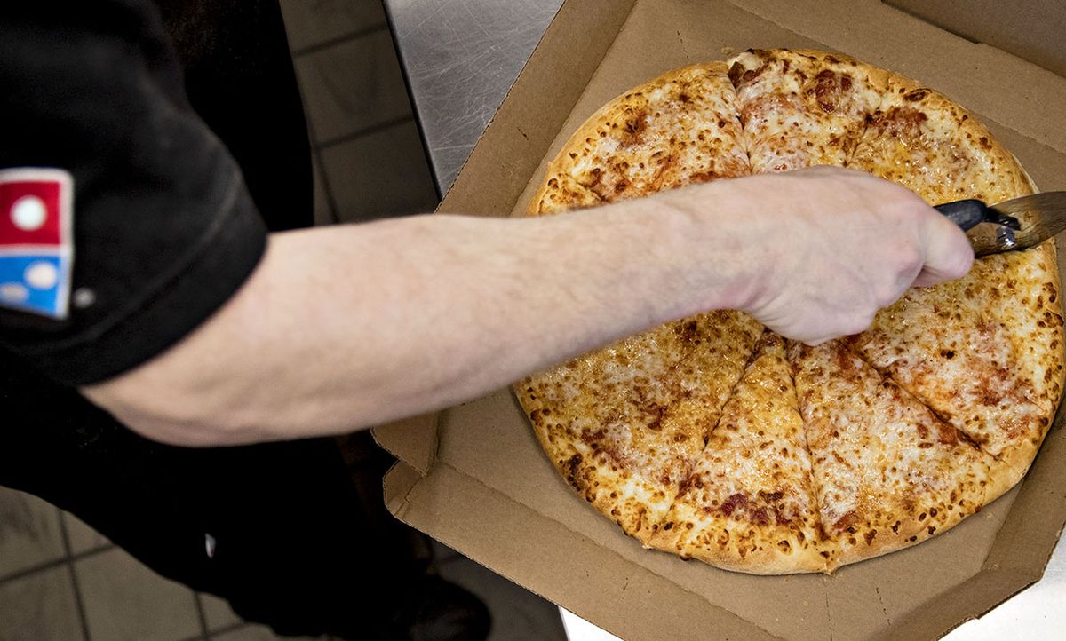 An employee cuts a pizza at a Domino's Pizza Inc. restaurant