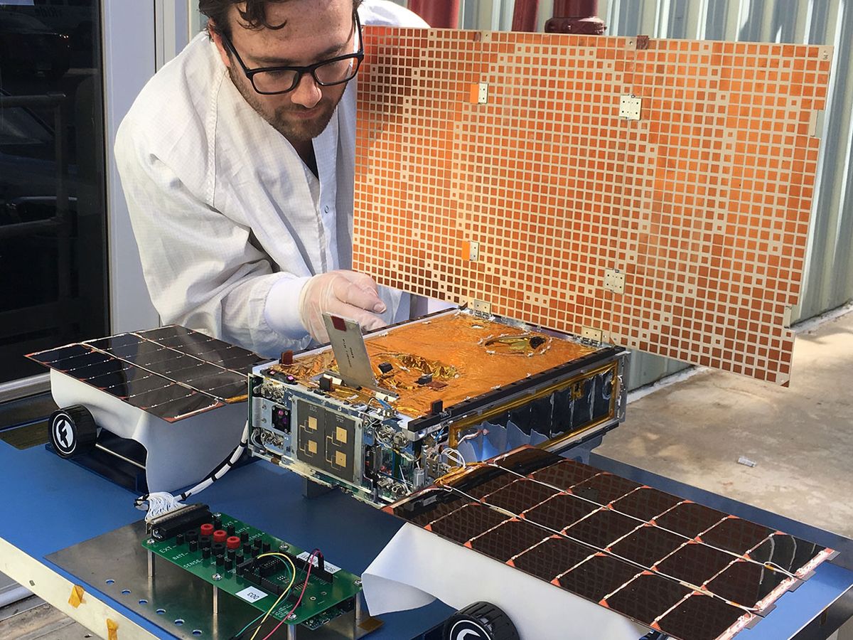 An engineer at the Jet Propolsion Lab uses sunlight to test the solar arrays on one of the Mars Cube One spacecraft .