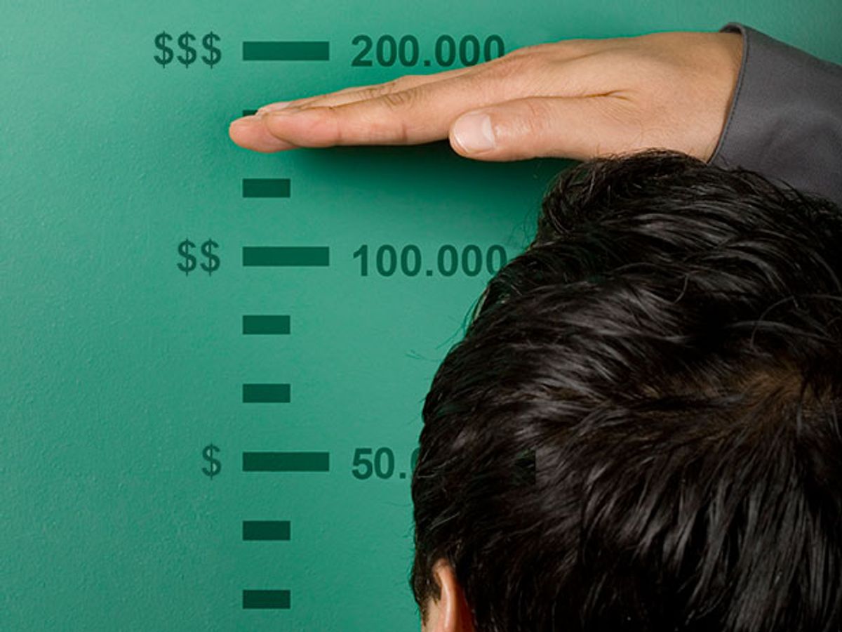 An engineer measures himself against a wall-mounted salary chart