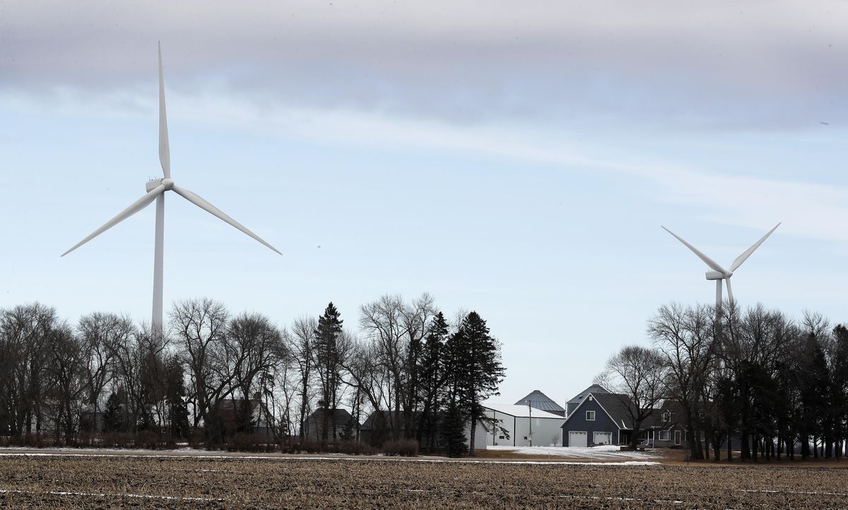 An image of a farm in Iowa with two large wind turbines in the background.
