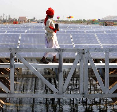 An Indian worker crosses solar panel canal in India.