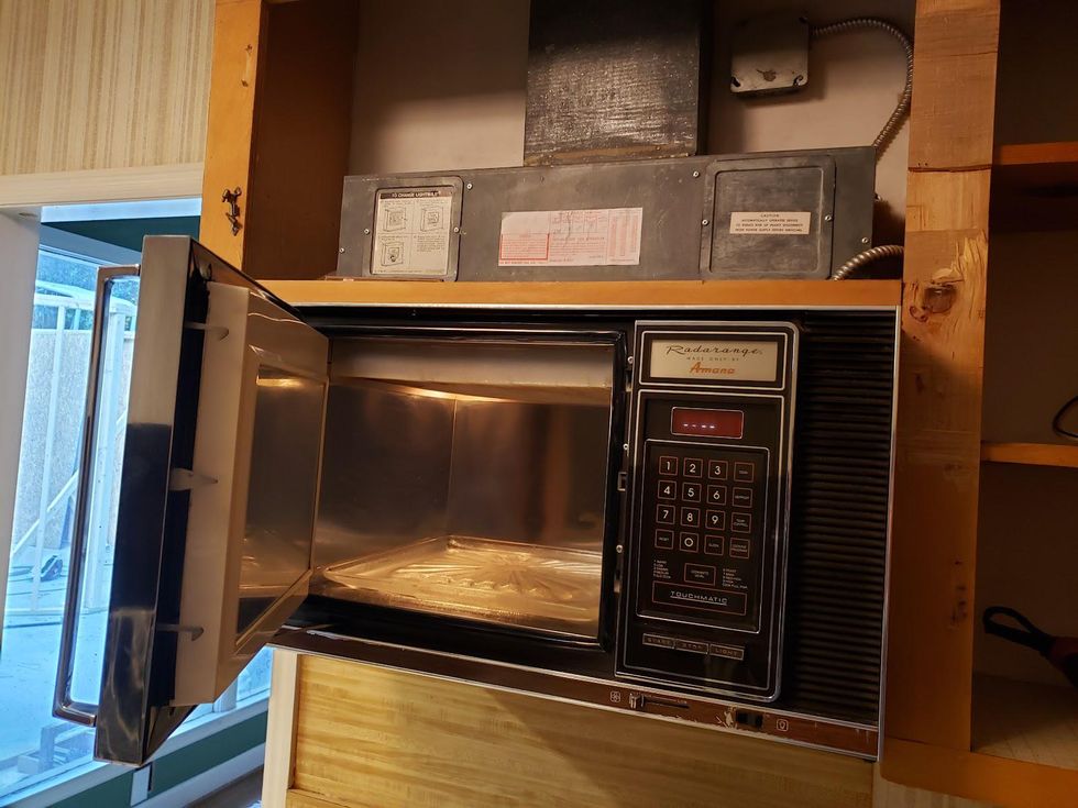An older model microwave oven with its door open.