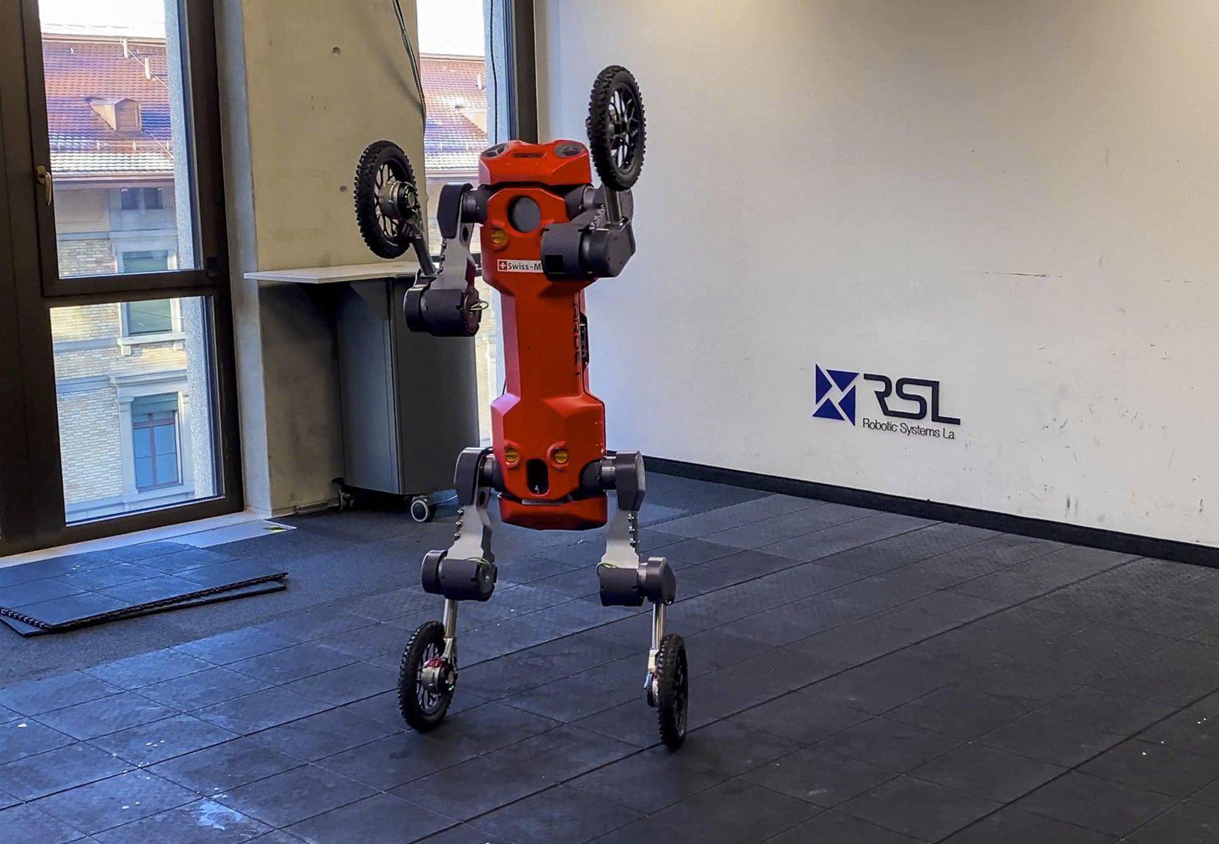 An orange quadruped robot with wheels at the end of its limbs stand upright on two wheels