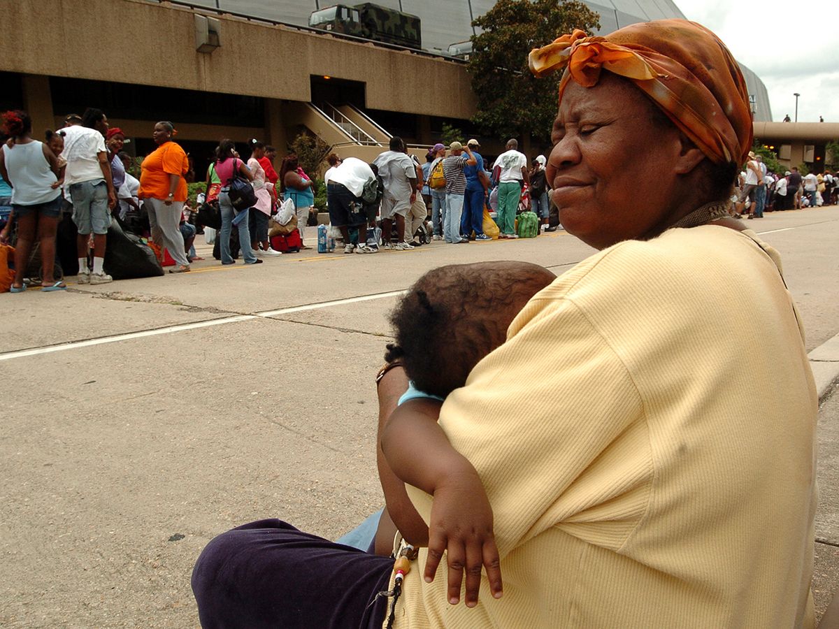 An unidentified woman holds a child while hurricane evacuees wait in line to enter the New Orleans Super Dome, August 2005.