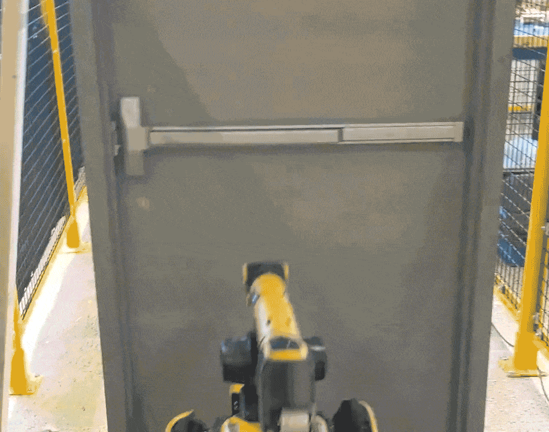 Animated gif from a video showing a yellow and black 4 legged robot which has an arm and opens a door and it closes after the robot goes through.