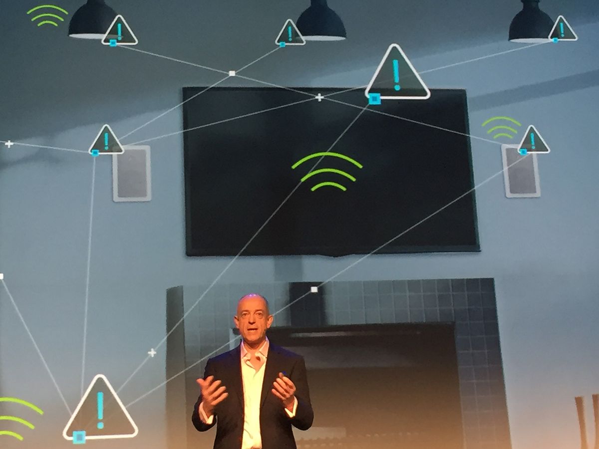 ARM CEO Simon Segars on a stage in front of a background indicating the internet of things