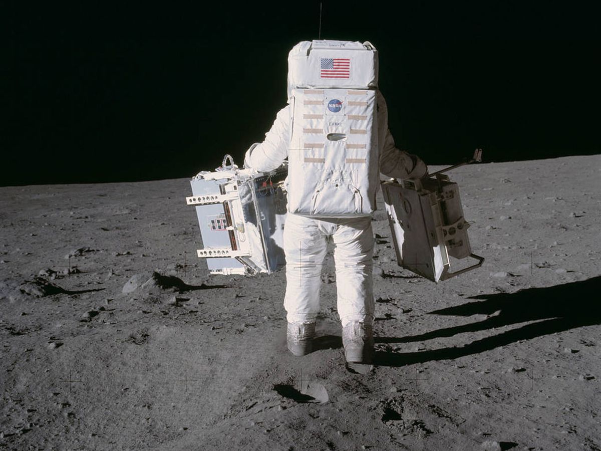 Astronaut Buzz Aldrin walks to place two components of the early Apollo scientific experiments package on the moon during the Apollo 11 mission.