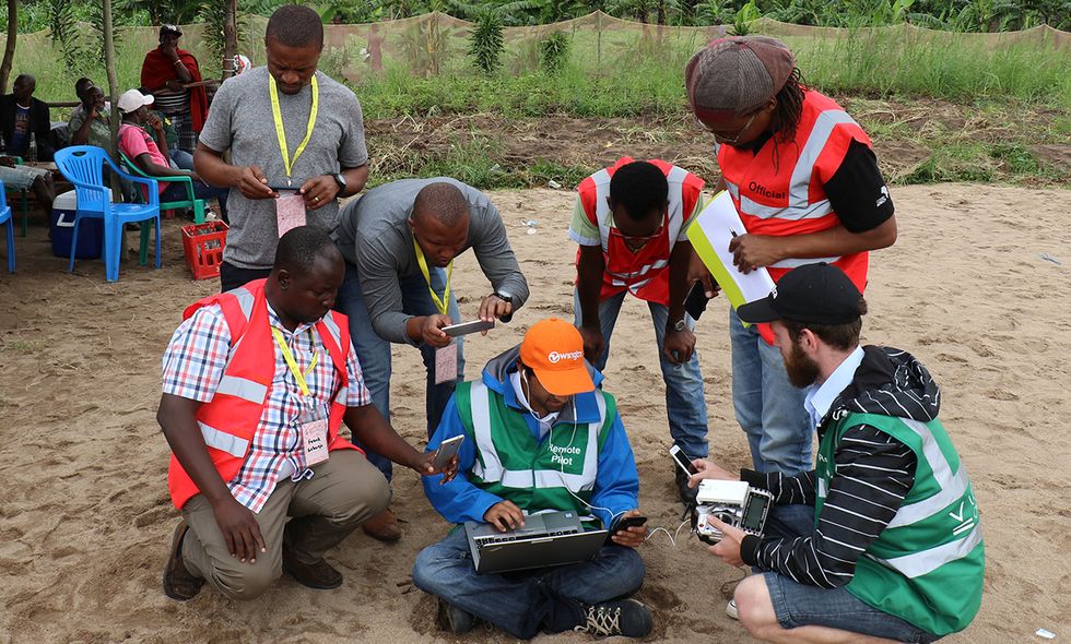 At the LVC launch area, safety-crew members and Juma community leaders gathered around two members of the Wingtra team who were monitoring their drone\u2019s flight.