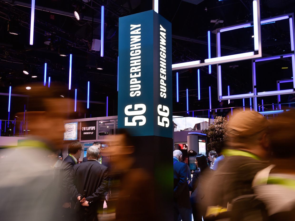 Attendeess pass by signage for 5G technology at the Intel booth during CES 2018 at the Las Vegas Convention Center on January 9, 2018 in Las Vegas, Nevada.