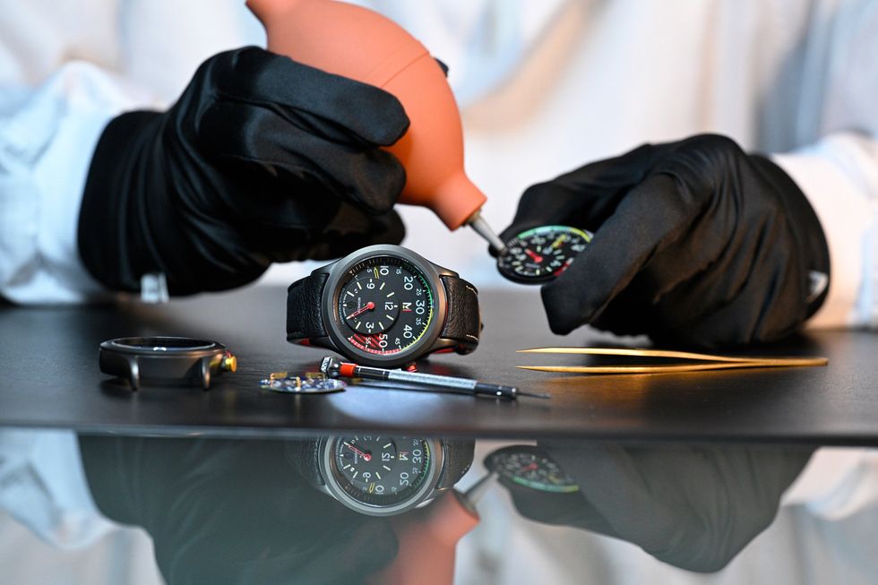 black rubber gloved hands putting a watch together