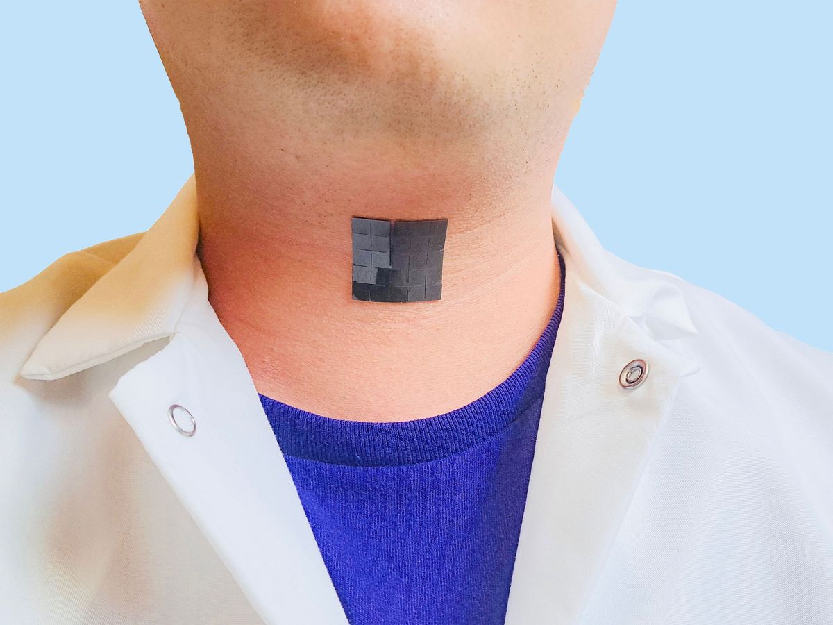 black square on person's neck wearing a white lab coat with a bright blue shirt