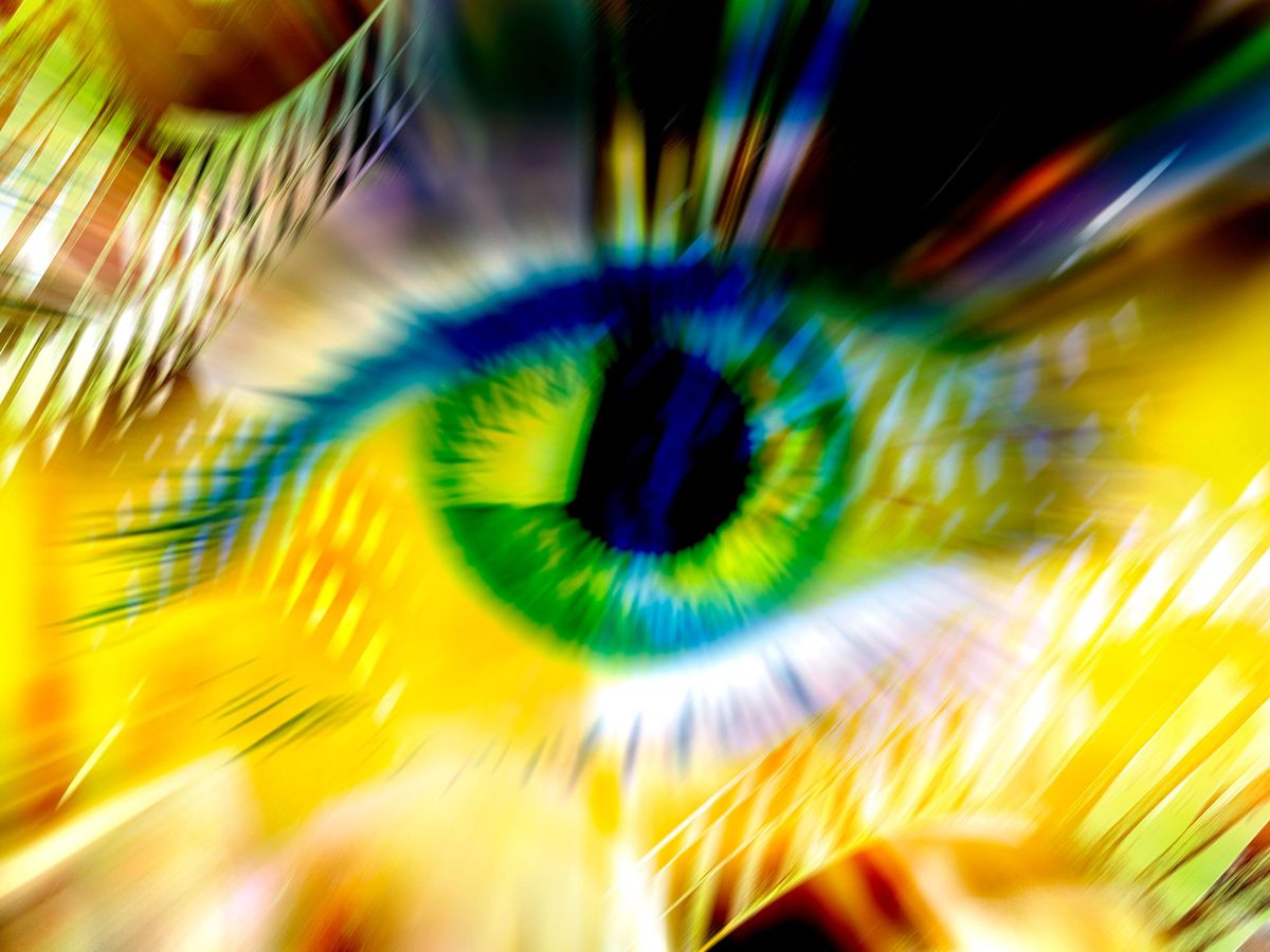 blurry close-up image of a green eye with a yellow background