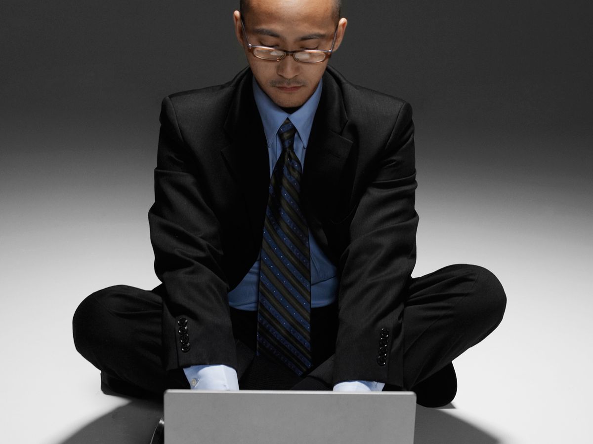 Business man sitting cross-legged in front of laptop.
