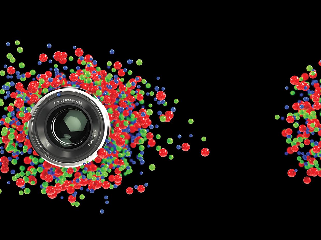 Camera lens surrounded by red, green and blue dots.