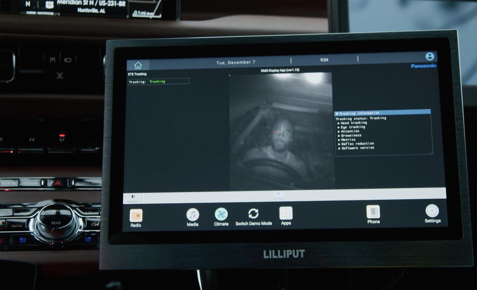 Close up of a car infotainment unit showing a man at the driving wheel, with eye-tracking technology overlayed on his face