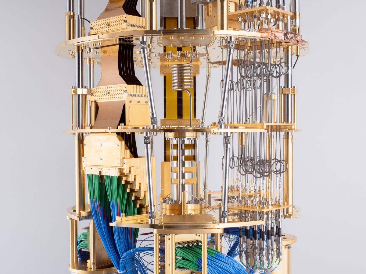 Close up of part of the golden multi-level cryostat, with myriad blue and green wires and other equipment.