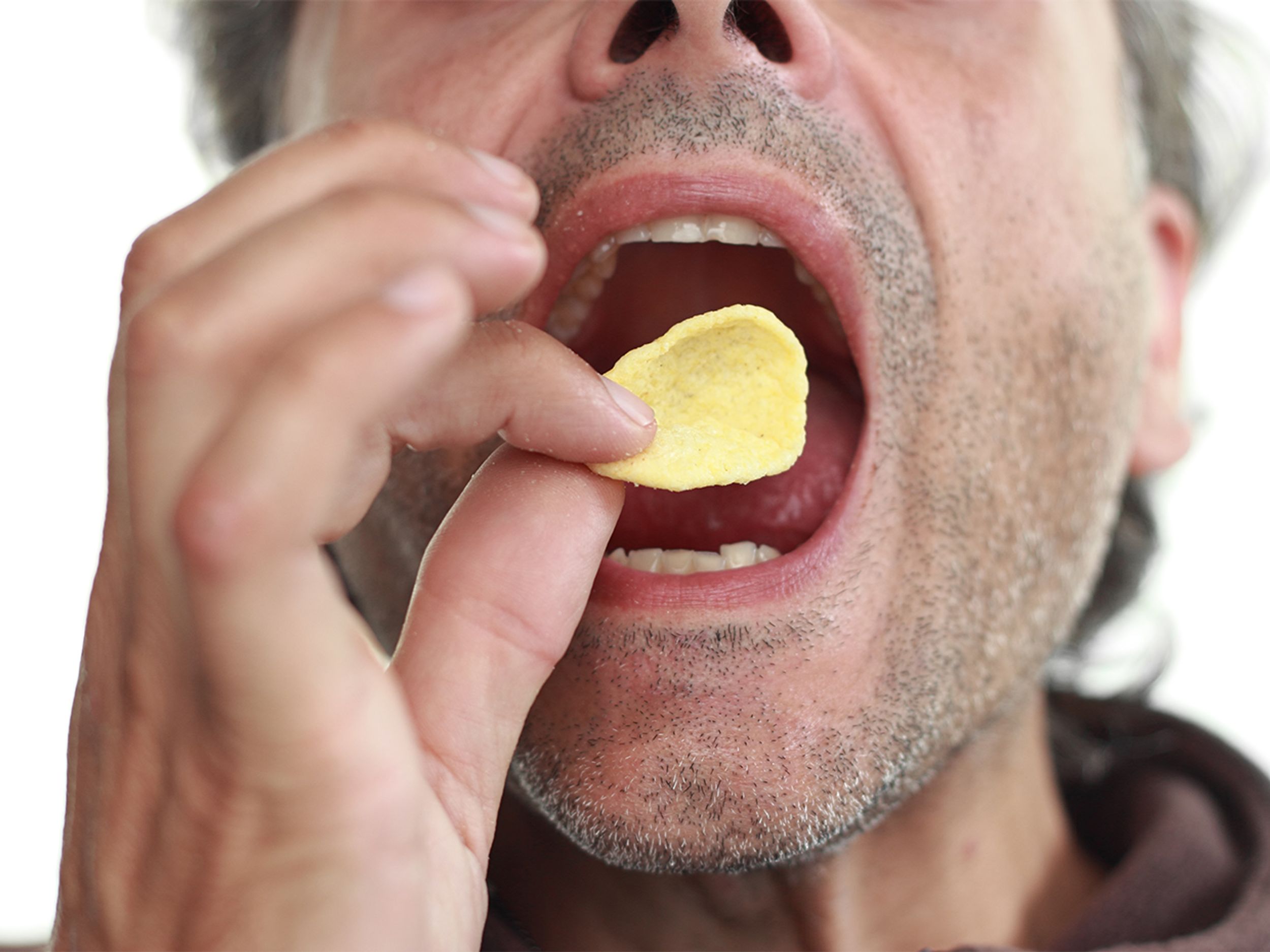 Close up photograph of a man eating a potato chip.