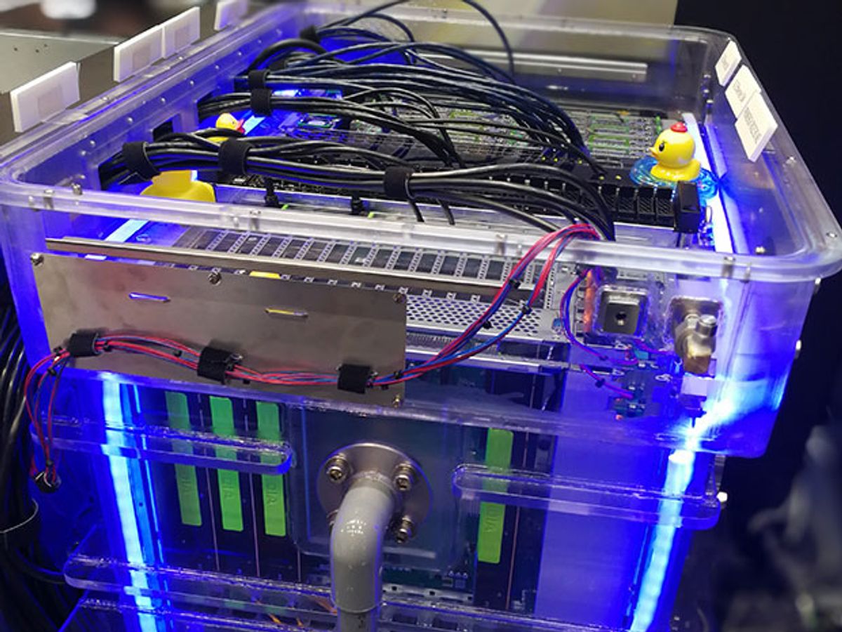 Computer immersed in liquid cooling system with blue light emanating from tank