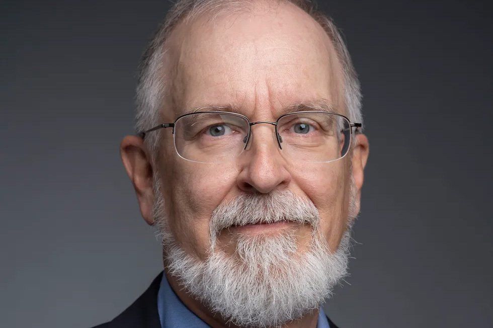 Crop of photo of a bearded man in glasses, blue shirt and jacket.