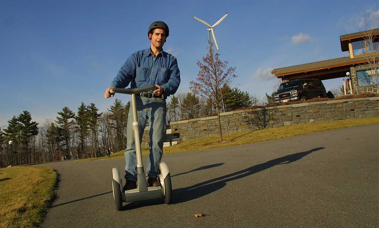 2002 photo of Dean Kamen, inventor of the Segway Human Transporter, riding a Segway outside his home and showing off it's self-balancing design.