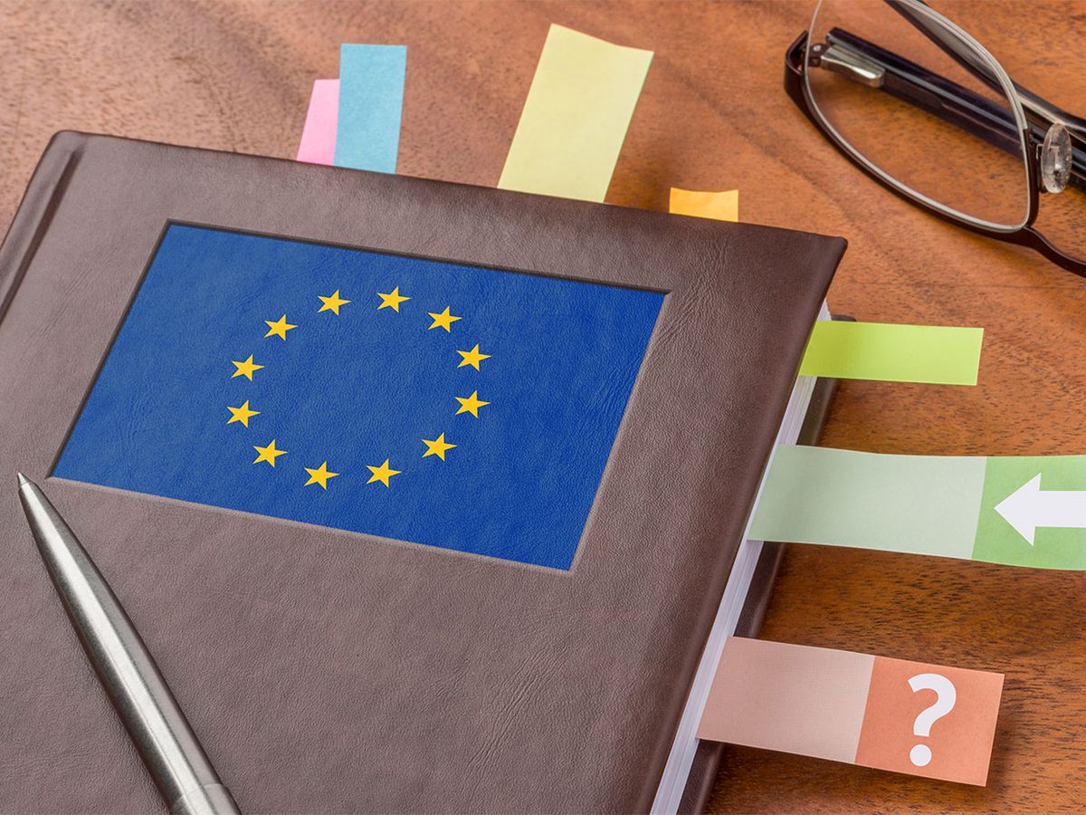 Desk with post-it filled notebook with EU flag on top