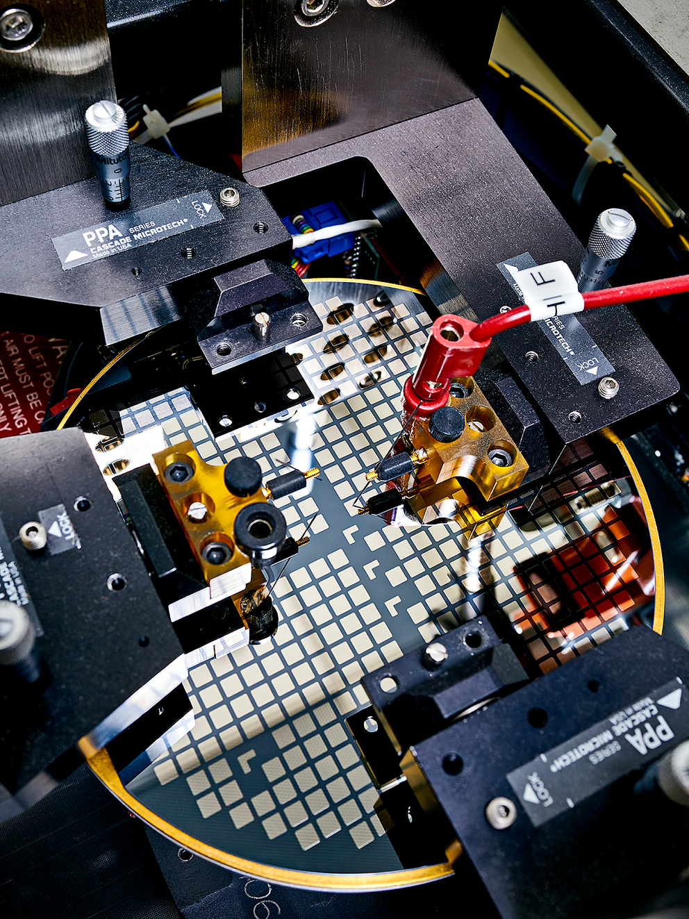 Devices on an advanced semiconductor wafer are tested with probes. 