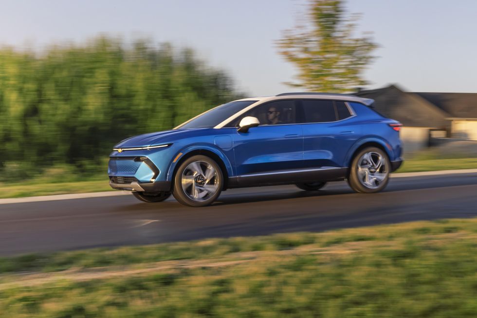  Driveru2019s side view of 2024 Chevrolet Equinox EV 3LT in Riptide Blue driving down a road