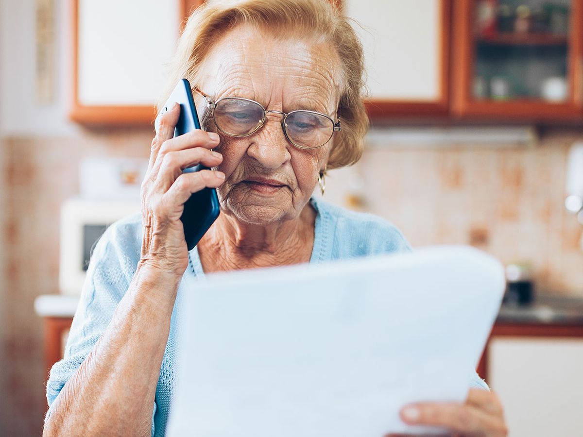 Elderly woman on the phone examining a bill.