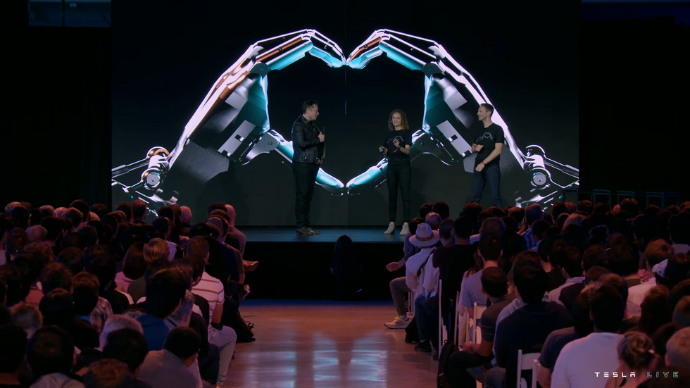 Elon Musk on stage with two Tesla engineers.