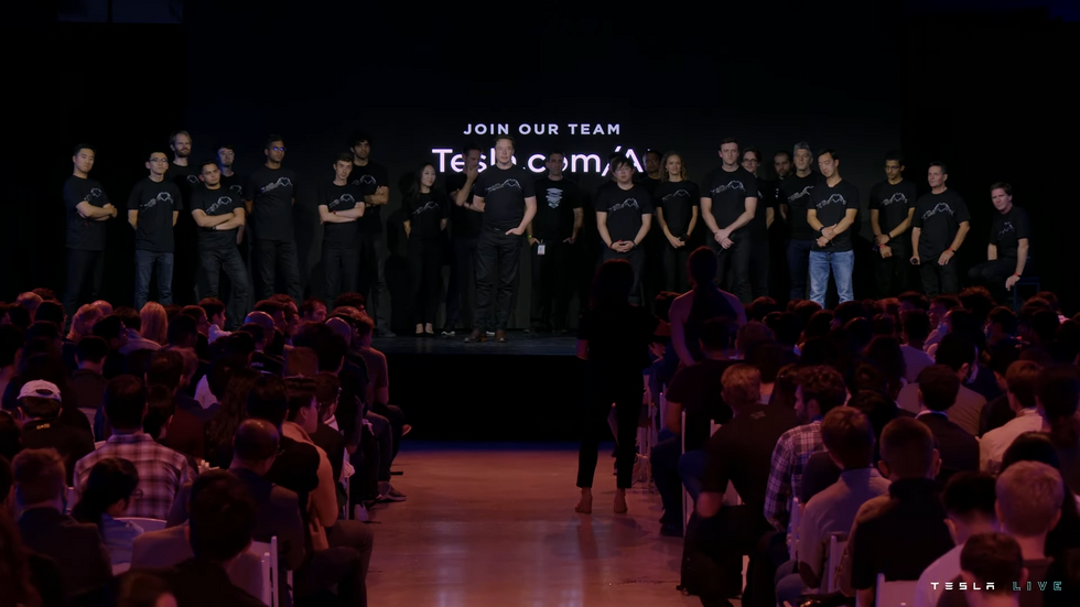 Elon Musk stands on stage with the Tesla AI team.