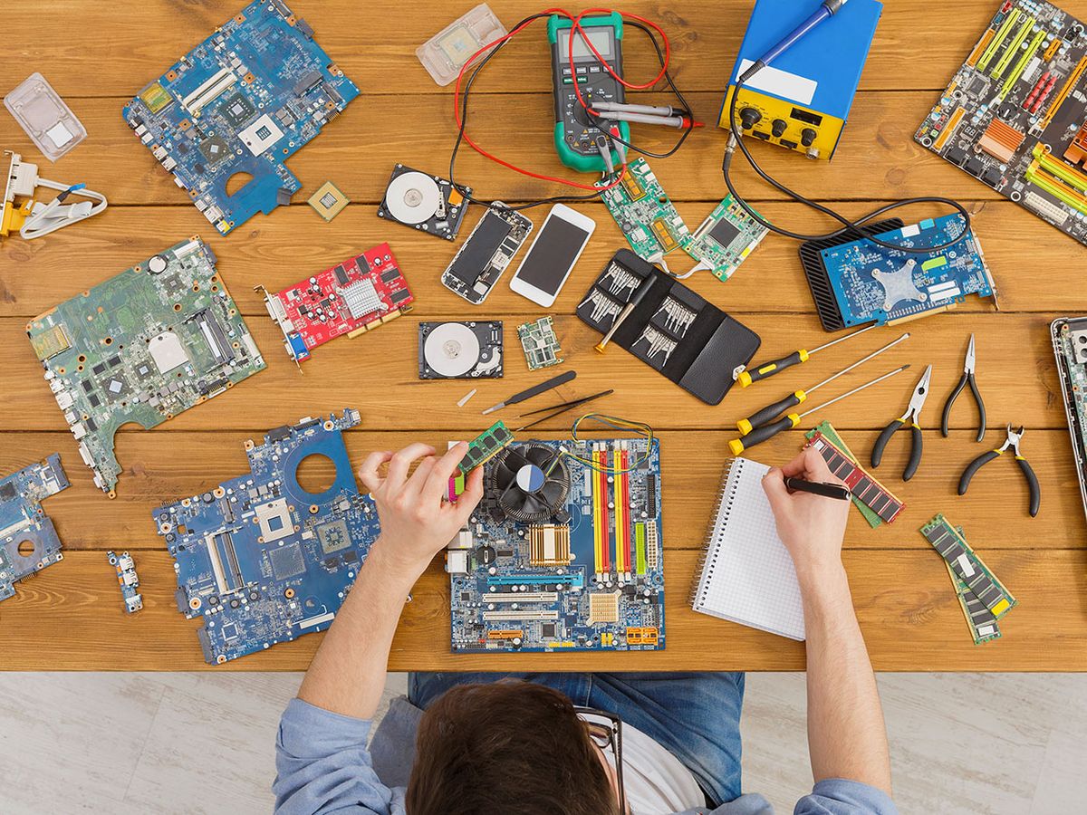 Engineer in front of a table covered in electronics and repair tools