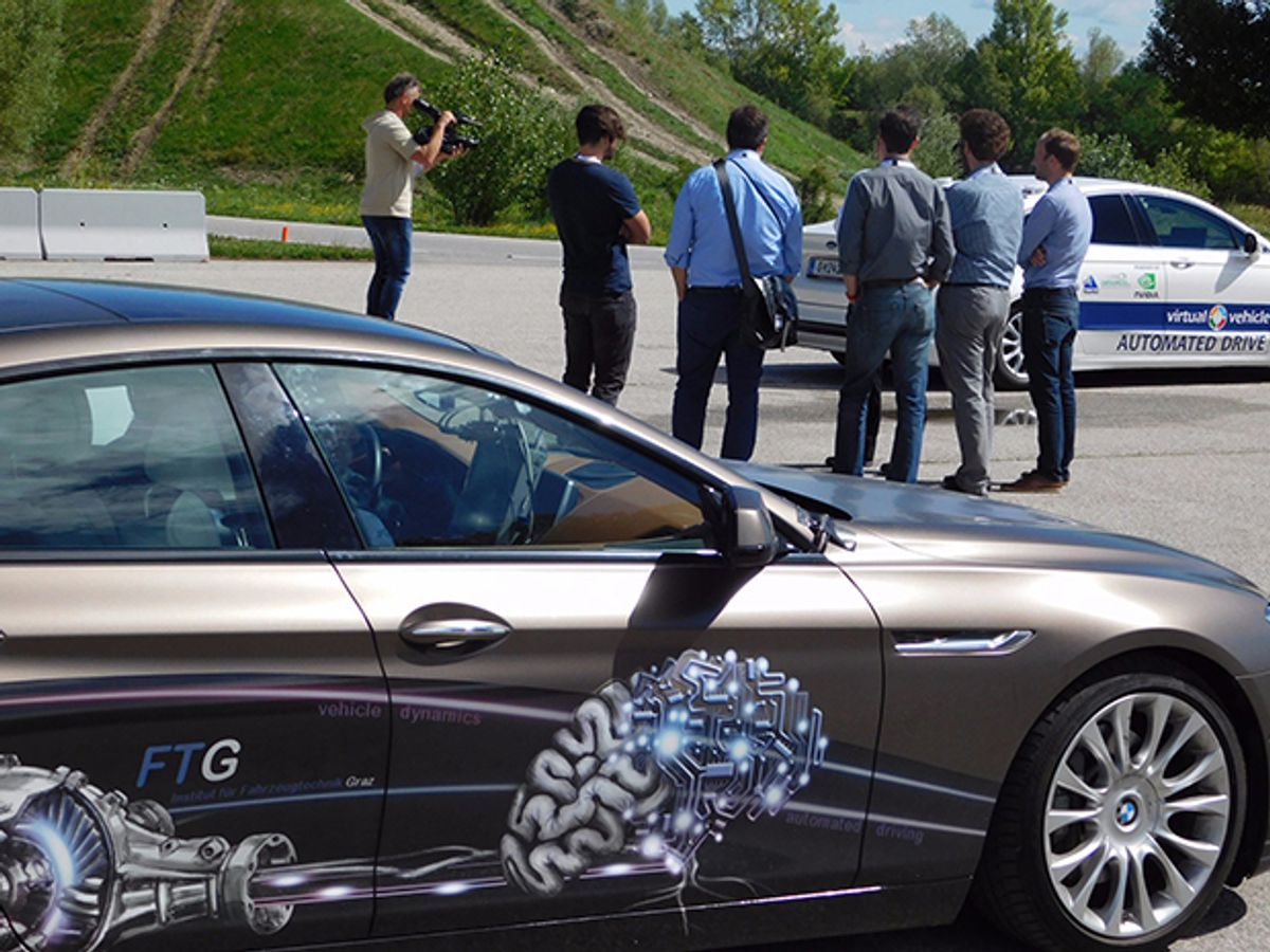 Engineers look at self-driving test vehicles at a track day