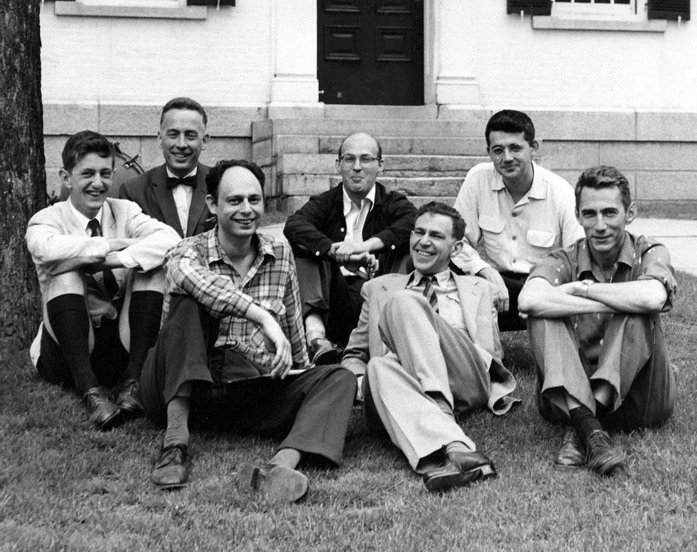 Image of men sitting on grass in front of a building for a 1956 workshop.