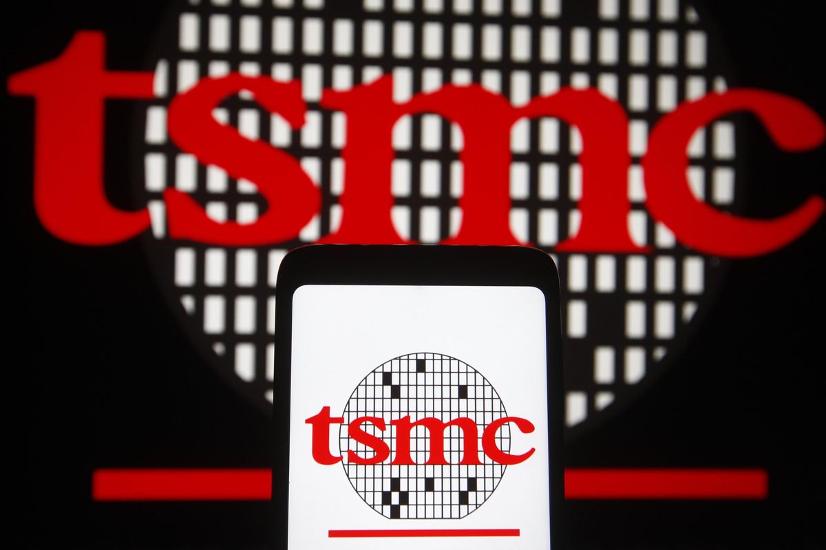 Foreground is a phone with the tsmc logo of tsmc in red and a circular semiconductor fab. Background is the same logo.