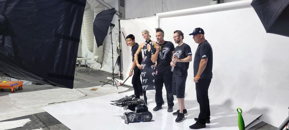 Four men and a woman pose admist professional photography lighting equipment in front of a track robot.