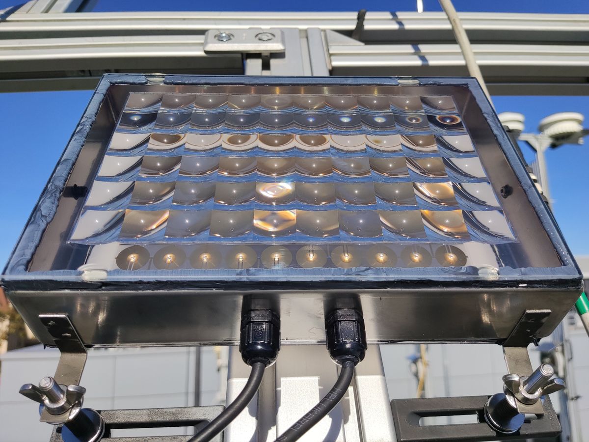 Fraunhofer ISE's technology, a rectangular metal box holding an array of micro-concentrated solar cells with planoconvex lenses is tested outside in the sun.