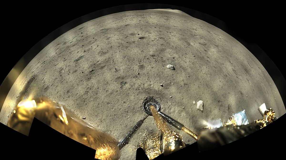 Grey pebble-strewn ground under a black sky, with one landing leg of a probe sitting on the surface.